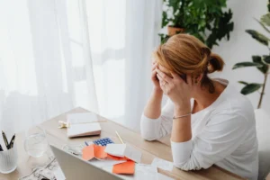 eine verzweifelte Frau sitzt an ihrem Rechner uns denkt über eine berufliche Neuausrichtung nach